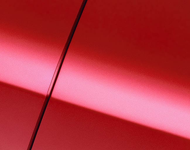 Surface of red sport sedan car, detail of metal fender and door of vehicle bodywork